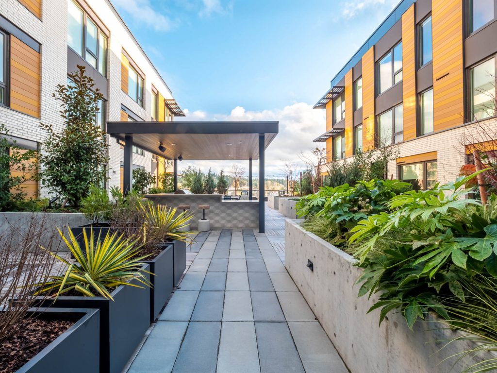 Covered outdoor grill area with peninsula bar counter, bar stool seating, and raised planters.