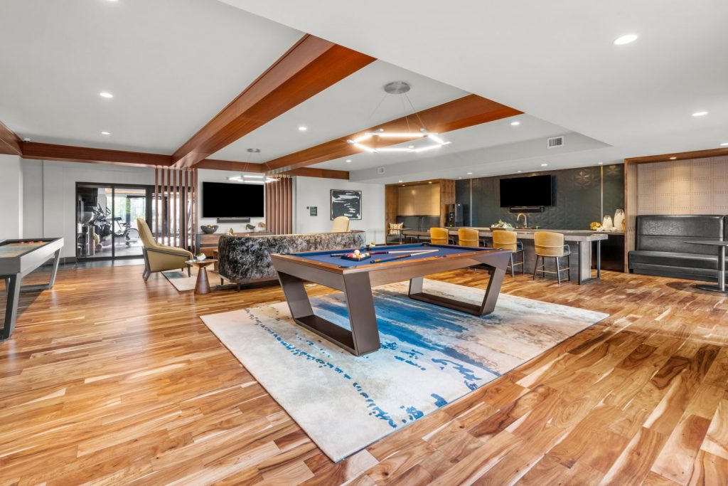 Club and games room with billiards table, shuffleboard, lounge seating, wall mounted TV’s, and a kitchenette with island bar seating.